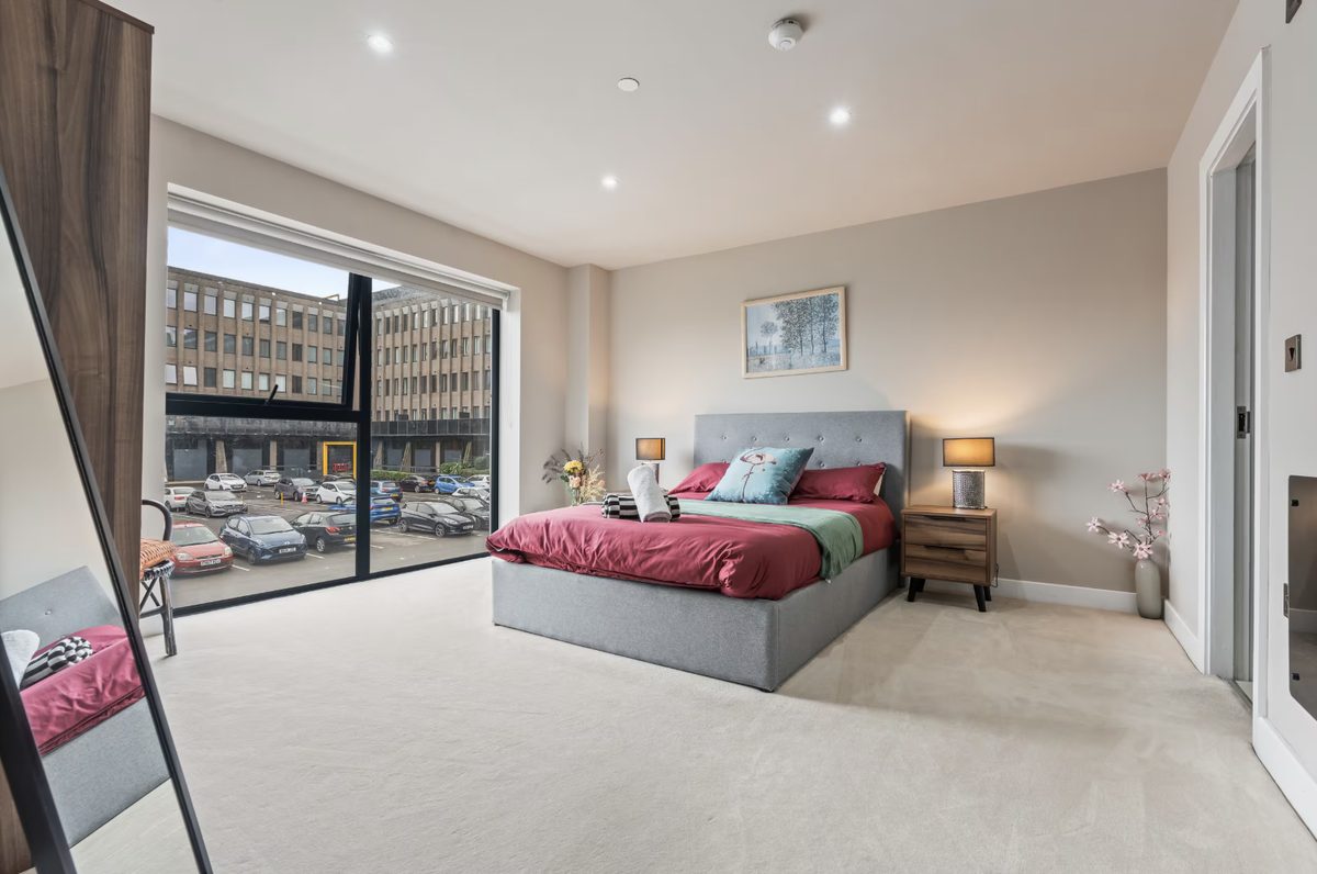 Bedroom with a grey bed and a floor-to-ceiling window